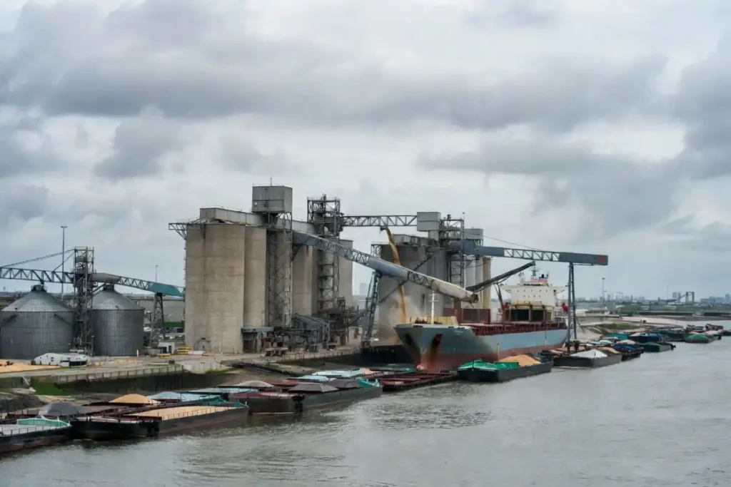 Large grain export terminal loading a cargo ship along the Mississippi River with barges in view
